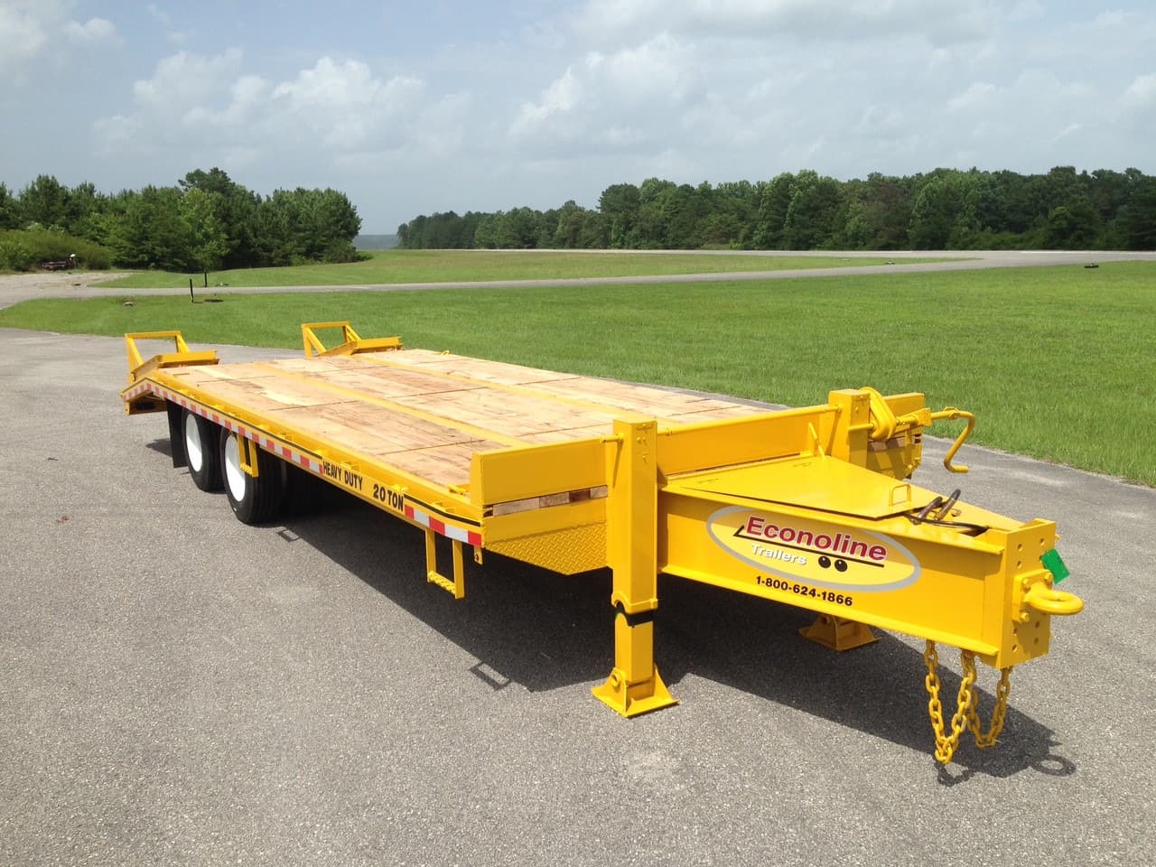 Twenty-foot deckover trailer with a full-width wooden deck over the wheels, ramps stowed and rear stabiliser jacks down